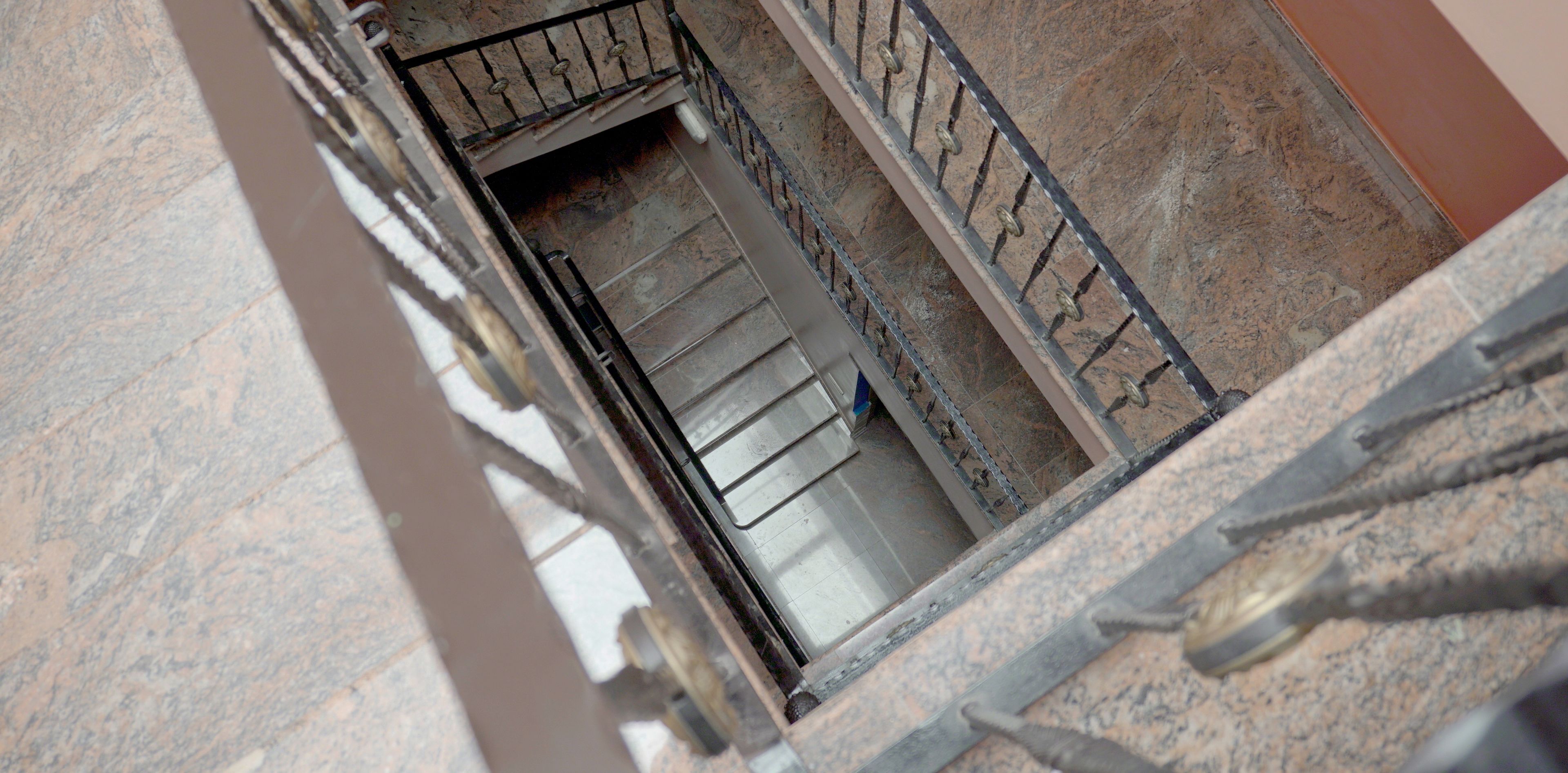Una escalera con barandillas de metal y un muro de piedra.