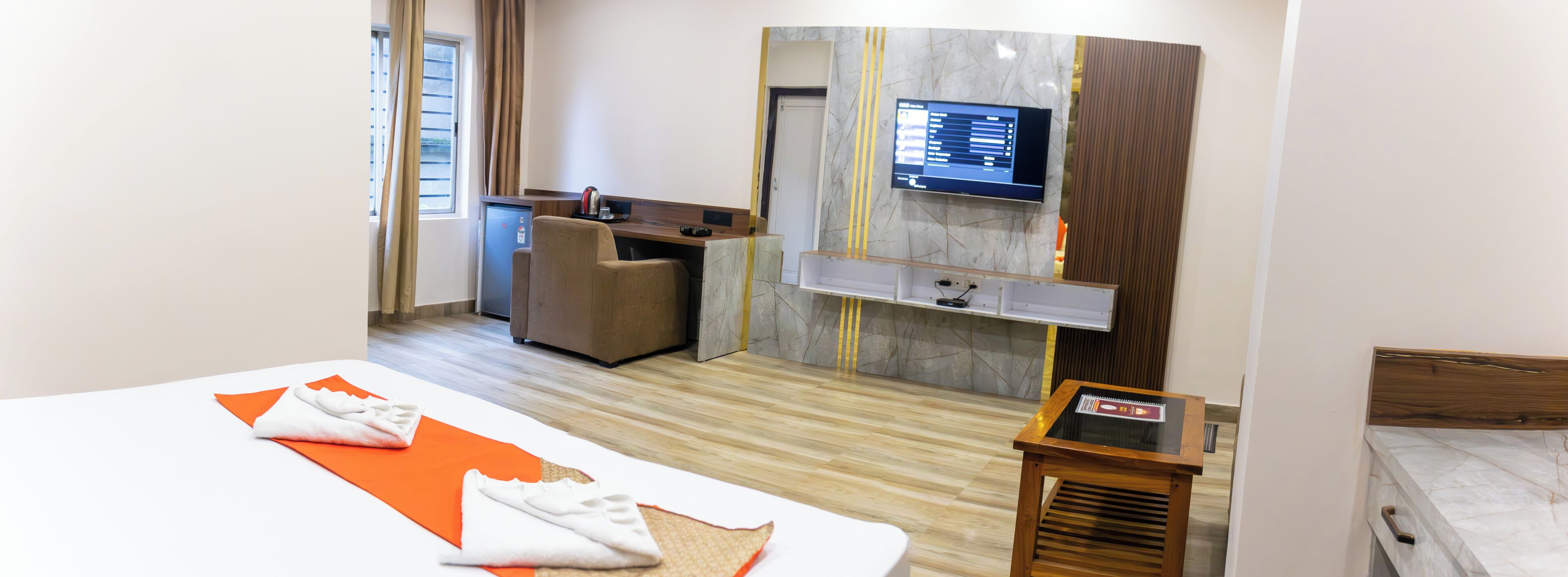 A hotel room with a bed, a desk, a television, and a small table.