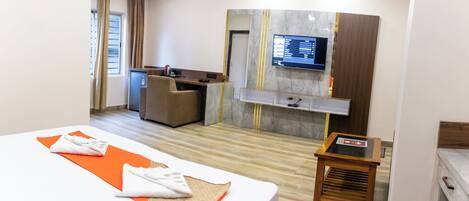 A hotel room with a bed, a desk, a television, and a small table.
