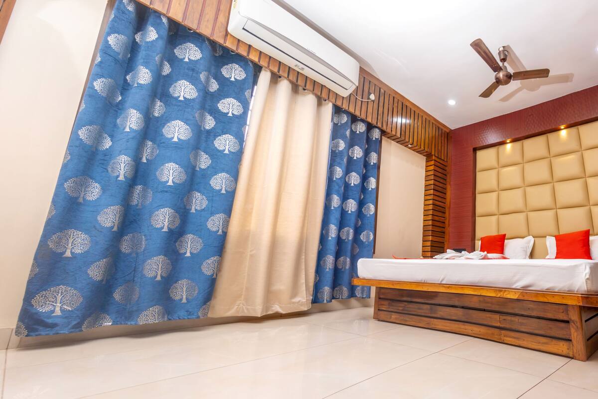 A bedroom with a bed, an air conditioner, a ceiling fan, and curtains.
