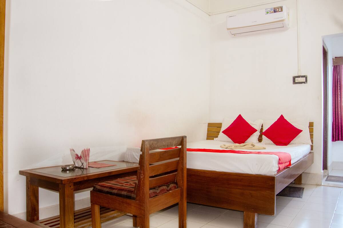 A bedroom with a wooden bed, a bedside table, and a chair.