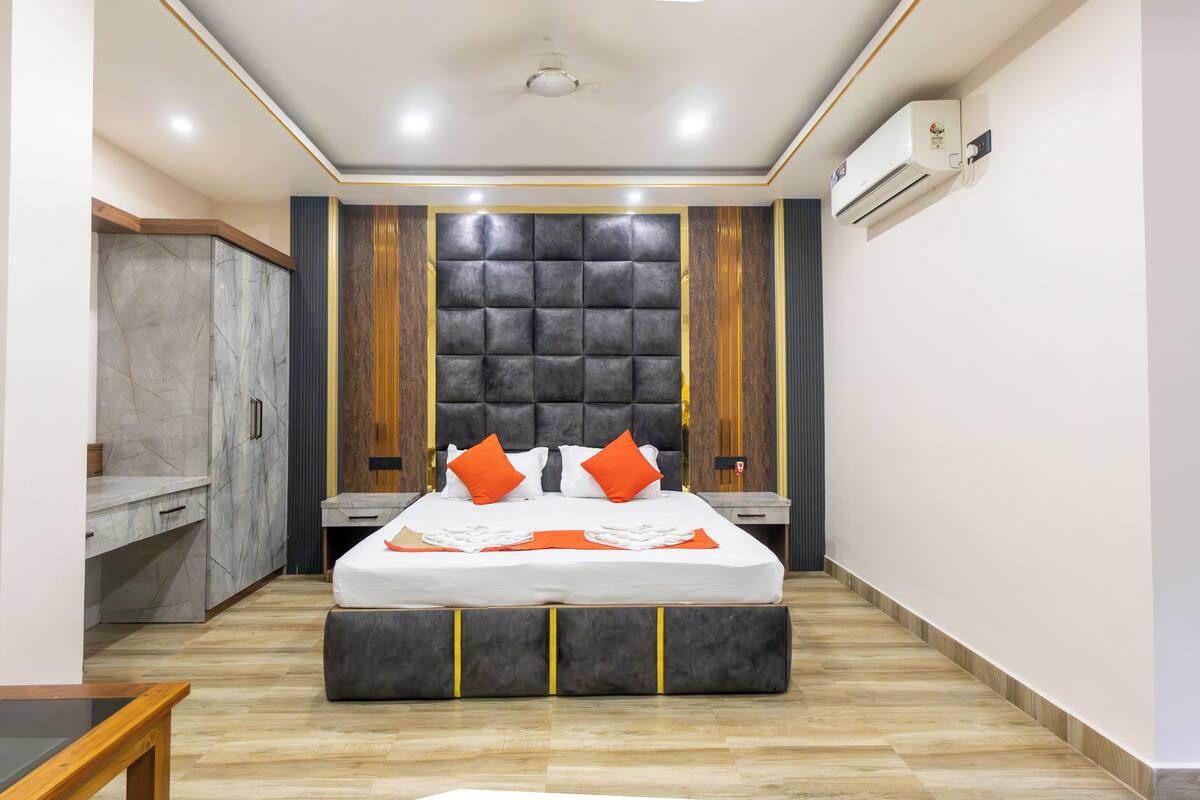 A modern bedroom with a large bed, a wardrobe, and a built-in bench.