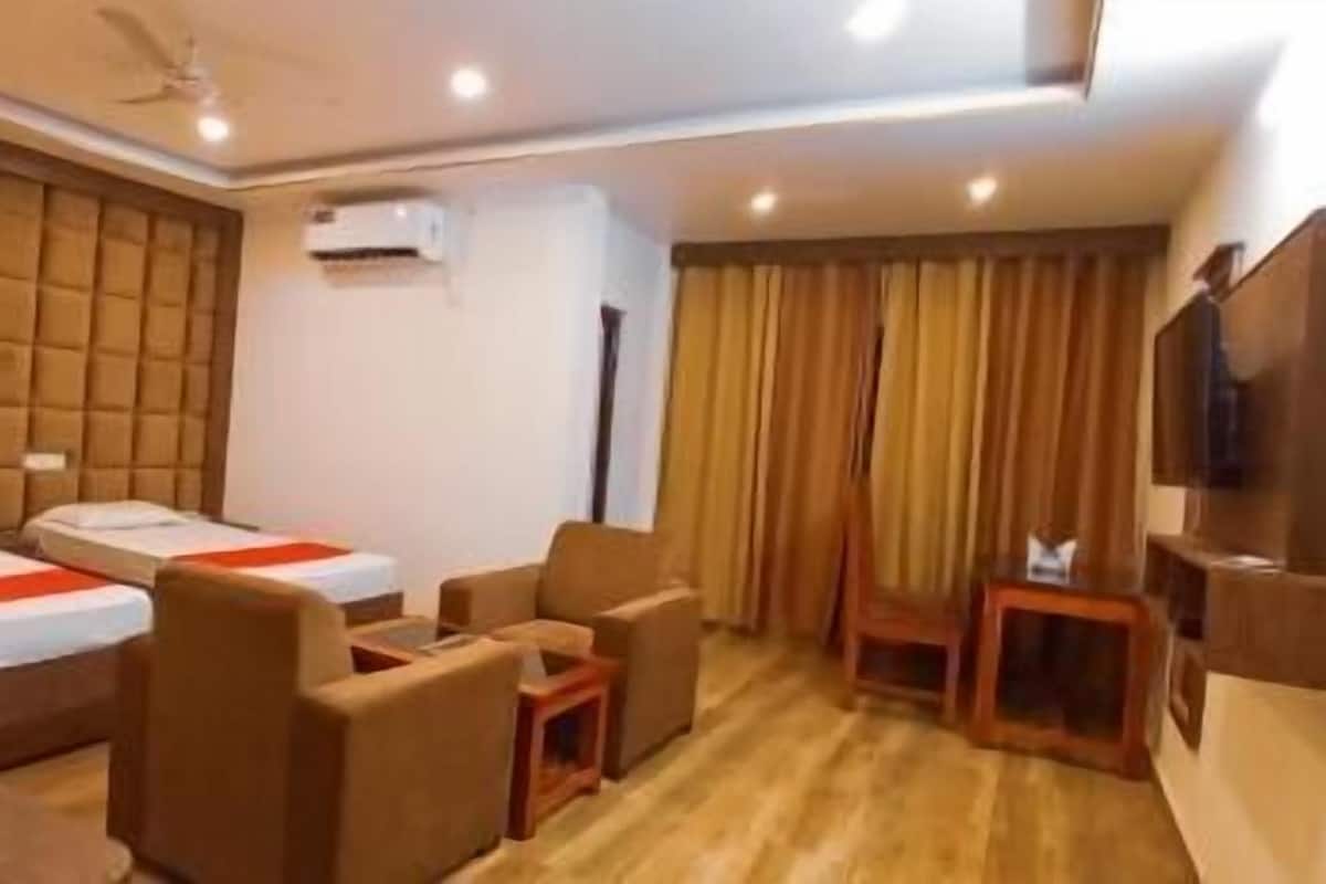 A hotel room with two beds, a sofa, a TV, and a ceiling fan.