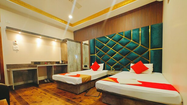 A hotel room with two beds, a desk, a mirror, and a wooden floor. - Hotel Nakshatra (Dima Hasao)