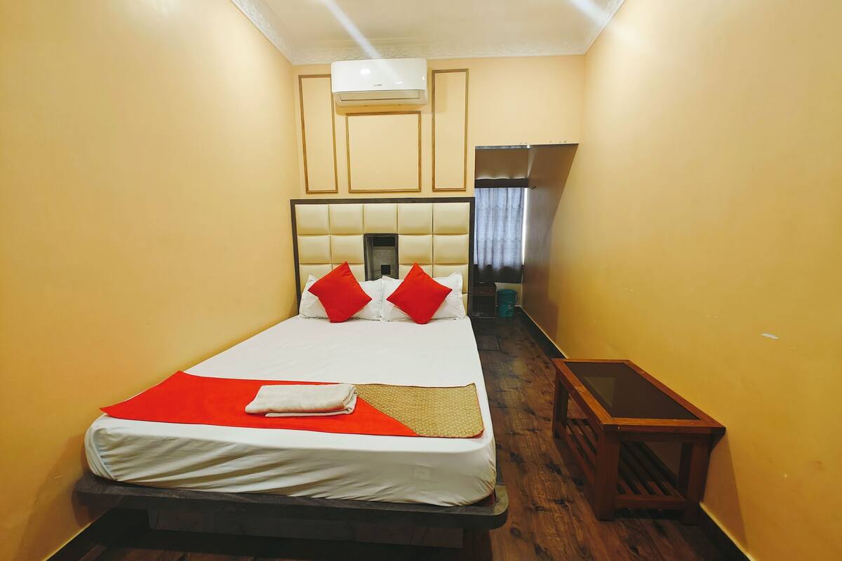 A hotel room with a bed, a nightstand, a mirror, and a window with curtains.