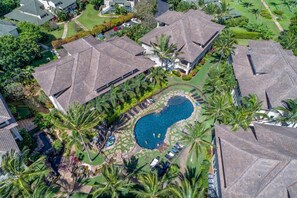 A residential area with multiple houses, a swimming pool, and lush greenery.
