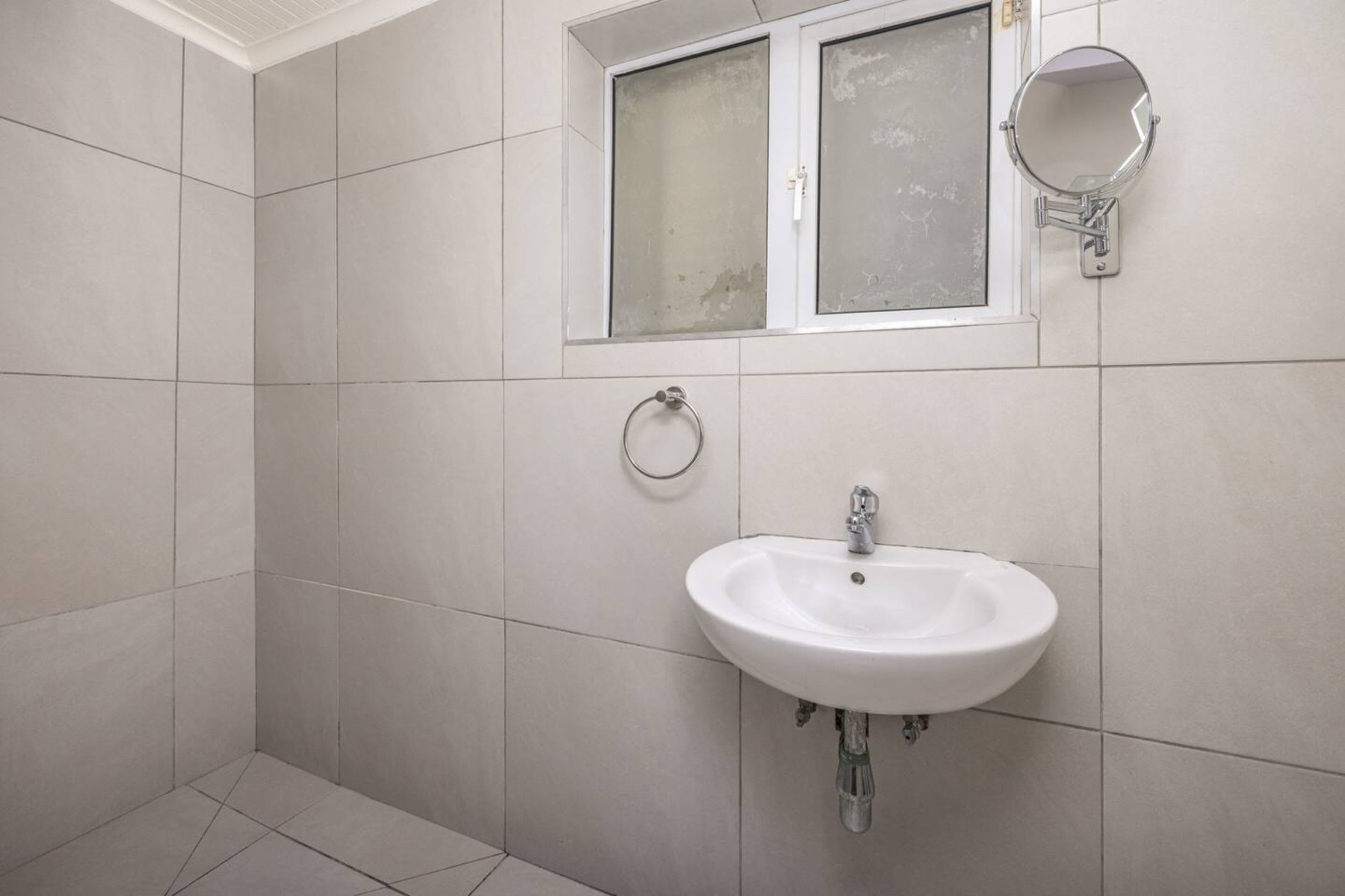 Ein Badezimmer mit einem weißen Waschbecken, einem Fenster mit Milchglas und einem wandmontierten Spiegel.