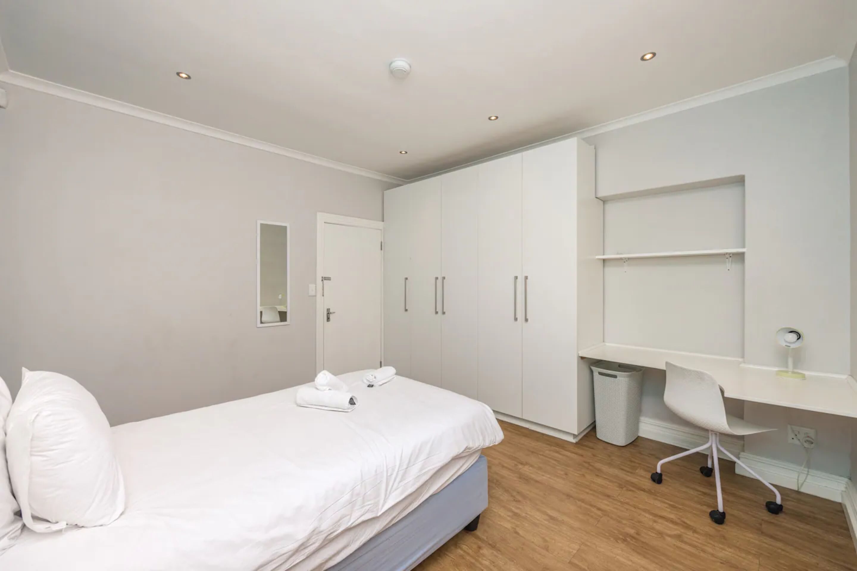 A bedroom with a bed, a desk, and a wardrobe.
