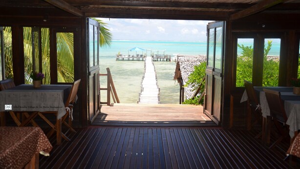 A wooden deck leading to a beach with a pier, tables, and chairs for dining. - Boraha Village (Nosy Boraha)
