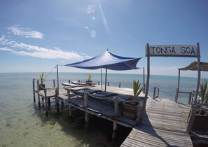 A wooden pier with lounge chairs and a sign reading "TONGA SOA".
