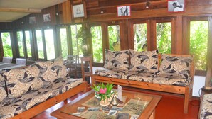 A wooden interior with a sofa set, a coffee table with decorative items, and framed pictures on the wall. - Boraha Village (Nosy Boraha)