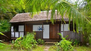 A wooden building with a thatched roof, surrounded by lush greenery and palm trees. - Boraha Village (Nosy Boraha)