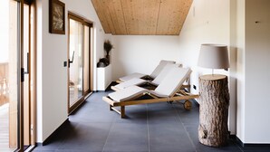 A modern room with a wooden ceiling, a large window, and a wooden floor. - Camina Suite & Spa (Cortina d'Ampezzo)