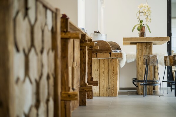 A wooden interior with a rustic design, featuring a wooden bench, a table with a vase of flowers, and a chair. - Camina Suite & Spa (Cortina d'Ampezzo)