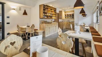 Un restaurante con mobiliario de madera, iluminación colgante y una zona central para comer.