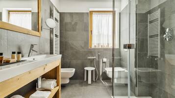 Un baño moderno con ducha envuelta en vidrio, un lavabo, un inodoro y un bidé.