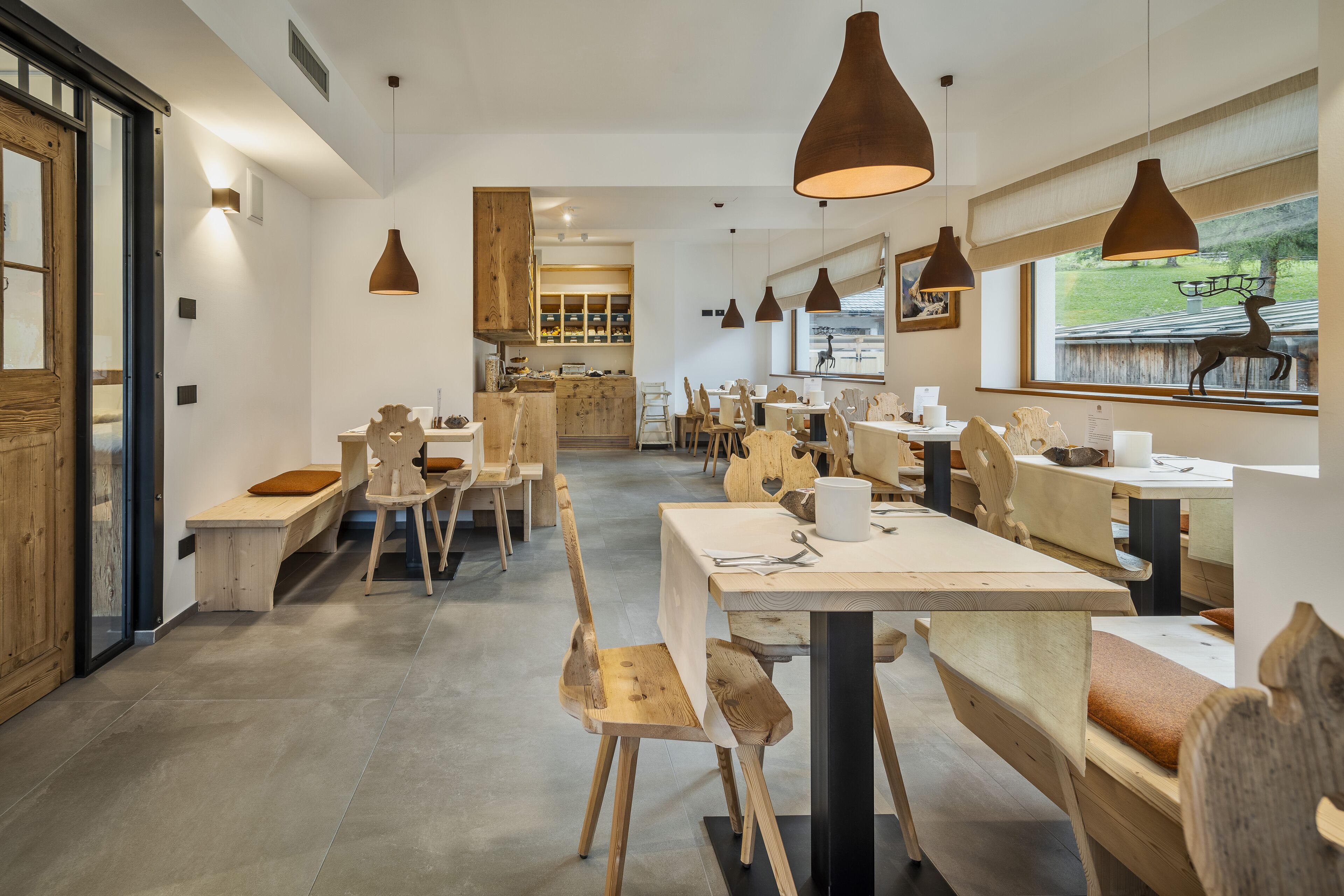 En restaurantindretning med træmøbler, hængende lamper og udsigt til det fri.