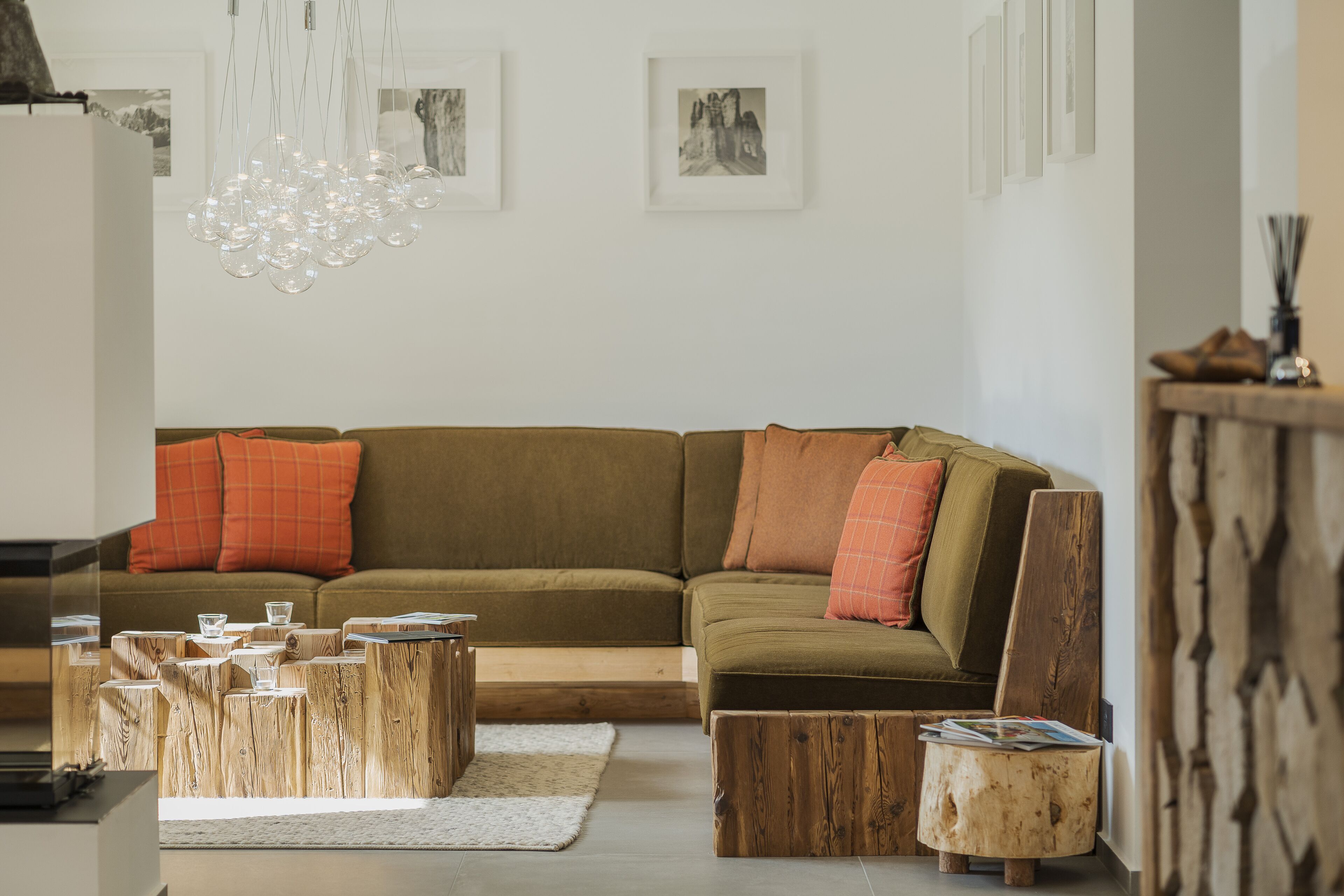 Un salon moderne avec un canapé d’angle, des tables basses en bois et des œuvres d’art accrochées aux murs.
