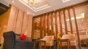 A lobby with a sofa, armchairs, a small table, and a decorative plant. - Bharawan Clarks Inn Express (Amritsar)