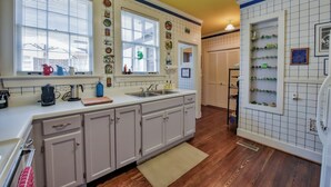 Cocina con armarios blancos, pileta doble y ventana con persianas.