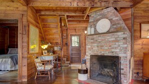 A cozy cabin interior with a wooden interior, a fireplace, a dining area, and a bed. - Charming lakefront cabin close to Acadia National Park (Franklin)