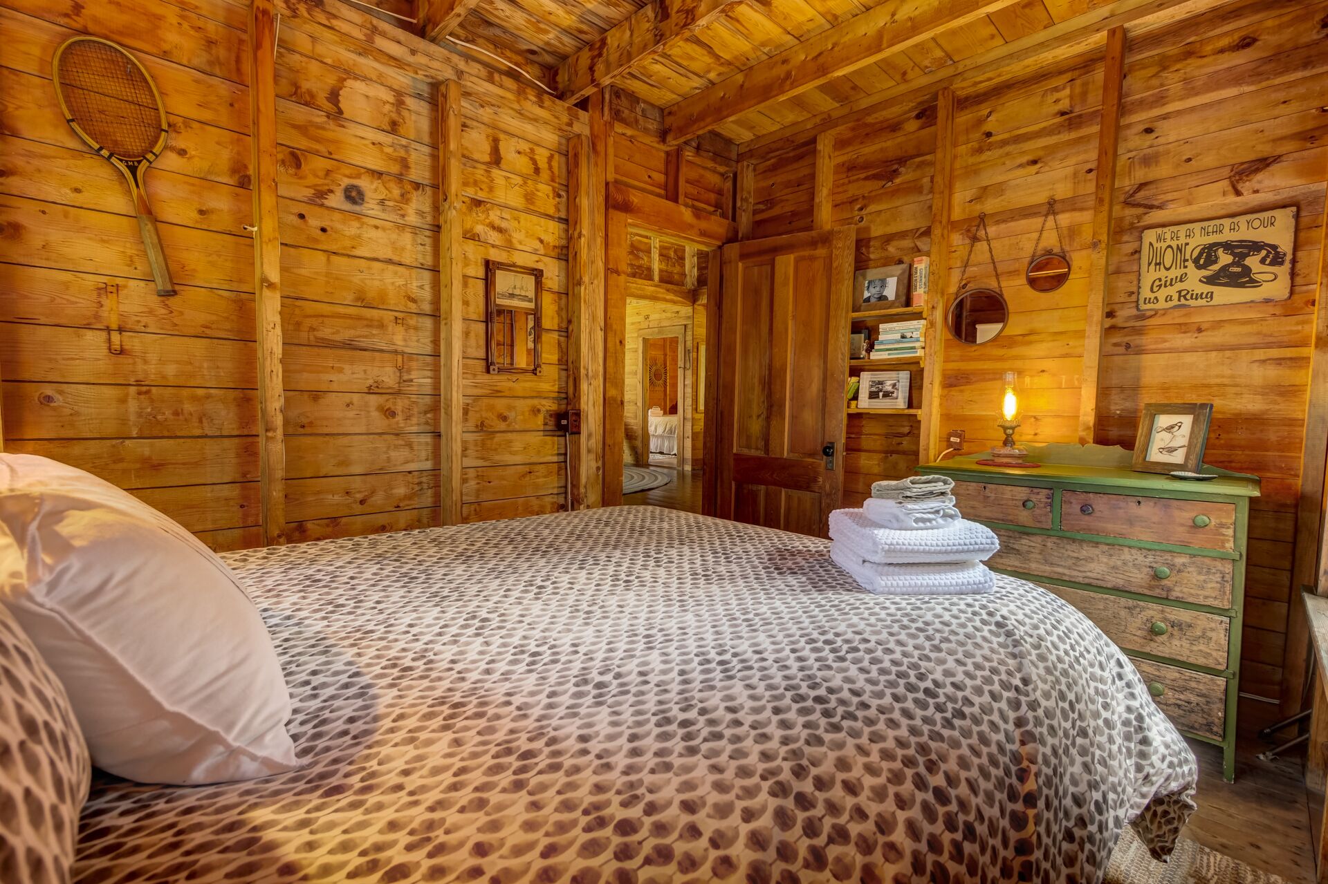 A wooden cabin room with a bed, a dresser, and a telephone.