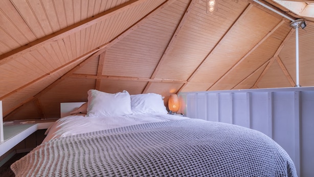 A cozy bedroom with a wooden ceiling, a bed with white linens, and a textured blanket. - Small Beach Cottage near the Coastal Trail and The Ritz (Half Moon Bay)