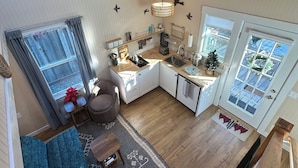 A spacious kitchen with a ceiling fan, a dining area with a sofa, and a view of the outside through a window. - Small Beach Cottage near the Coastal Trail and The Ritz (Half Moon Bay)