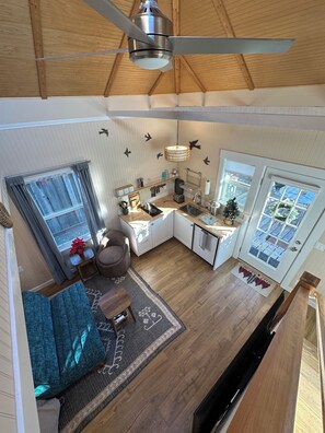 A spacious kitchen with a ceiling fan, a dining area with a sofa, and a view of the outside through a window. - Small Beach Cottage near the Coastal Trail and The Ritz (Half Moon Bay)
