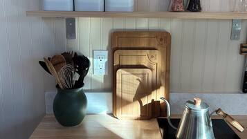 A kitchen with a wooden cutting board, a kettle, and labeled containers for tea, coffee, and sugar.