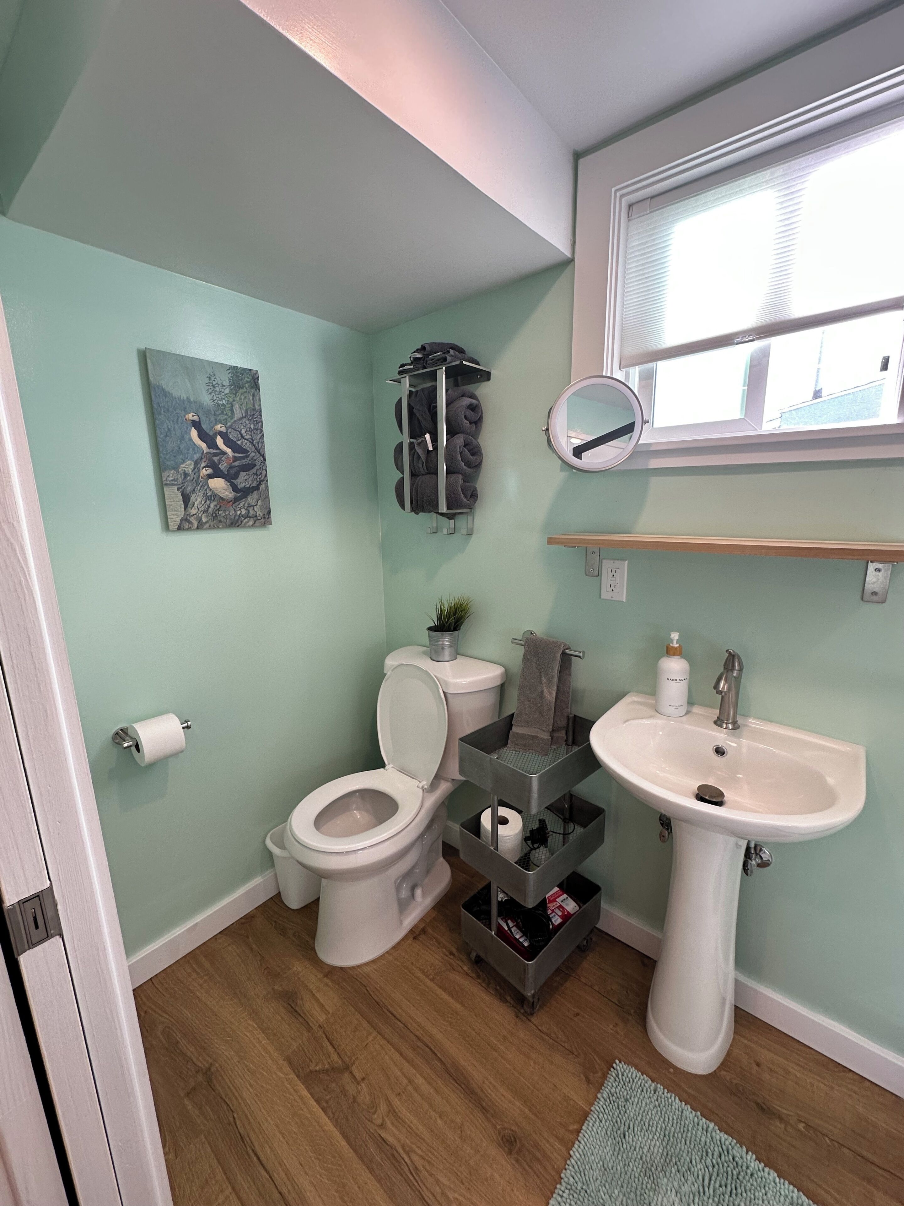 Ein Badezimmer mit Toilette, Waschbecken, Handtuchhalter und einem Bild an der Wand.