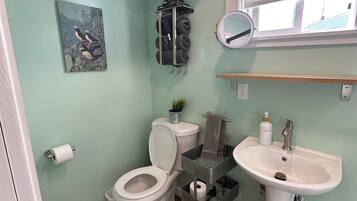 Ein Badezimmer mit Toilette, Waschbecken, Handtuchhalter und einem Bild an der Wand.