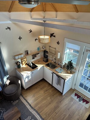 A compact kitchen with white cabinets, a wooden countertop, a hanging light fixture, and a window with a view. - Small Beach Cottage near the Coastal Trail and The Ritz (Half Moon Bay)