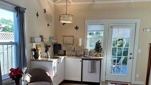 A compact kitchen with a dining area, a small seating space, and a large window. - Small Beach Cottage near the Coastal Trail and The Ritz (Half Moon Bay)