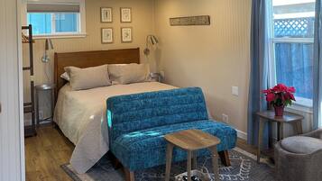 Una camera da letto con un letto, una panca imbottita blu, un piccolo tavolo di legno e un decorativo arazzo a forma di cavalluccio marino.