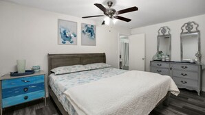 A bedroom with a bed, a dresser, a mirror, and two wall-mounted paintings. - POOL House on the Kemah Boardwalk w BIKES (Kemah)