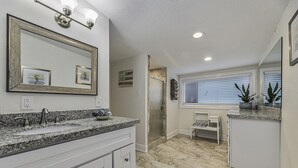 A bathroom with a granite countertop sink, a large mirror, and a window with blinds. - POOL House on the Kemah Boardwalk w BIKES (Kemah)