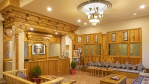 Un intérieur en bois comprenant un comptoir d’accueil, un espace salon et un lustre.