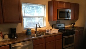 A kitchen with wooden cabinets, stainless steel appliances, a dishwasher, and a window with blinds. - Charming! Near Microsoft Mt Pleasant - Sleeps 8 (Kenosha)