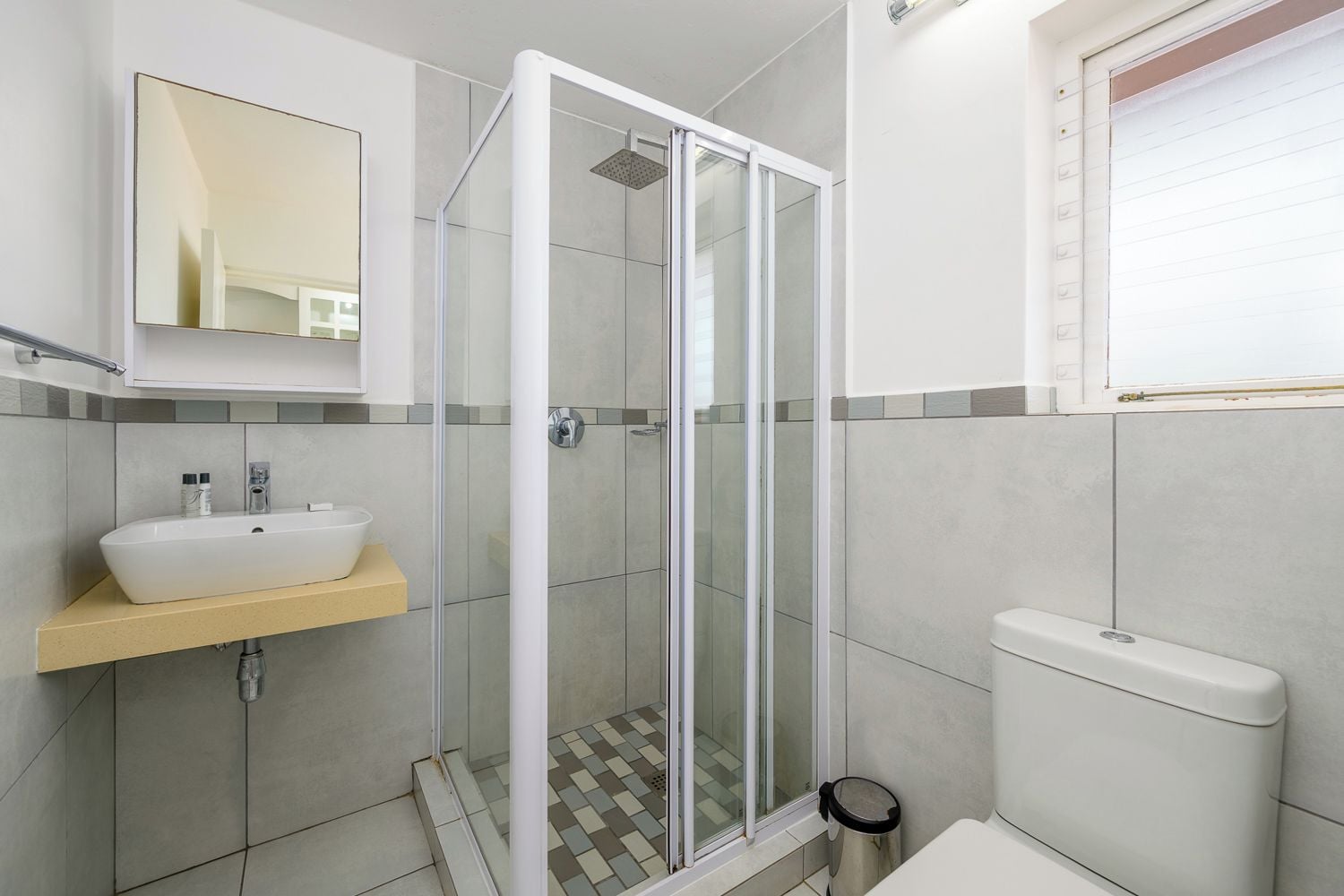 A bathroom with a glass-enclosed shower, a white sink, and a toilet.