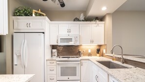 A modern kitchen with white cabinetry, a built-in microwave, an oven, a sink, and a coffee maker. - Bayfront - in the Heart of Naples!  (Naples)