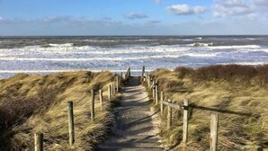 Un sendero de madera que lleva a la playa, con olas rompiendo al fondo.