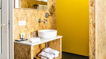 Un baño con pared de madera, un lavamanos blanco, un espejo y una pared amarilla.