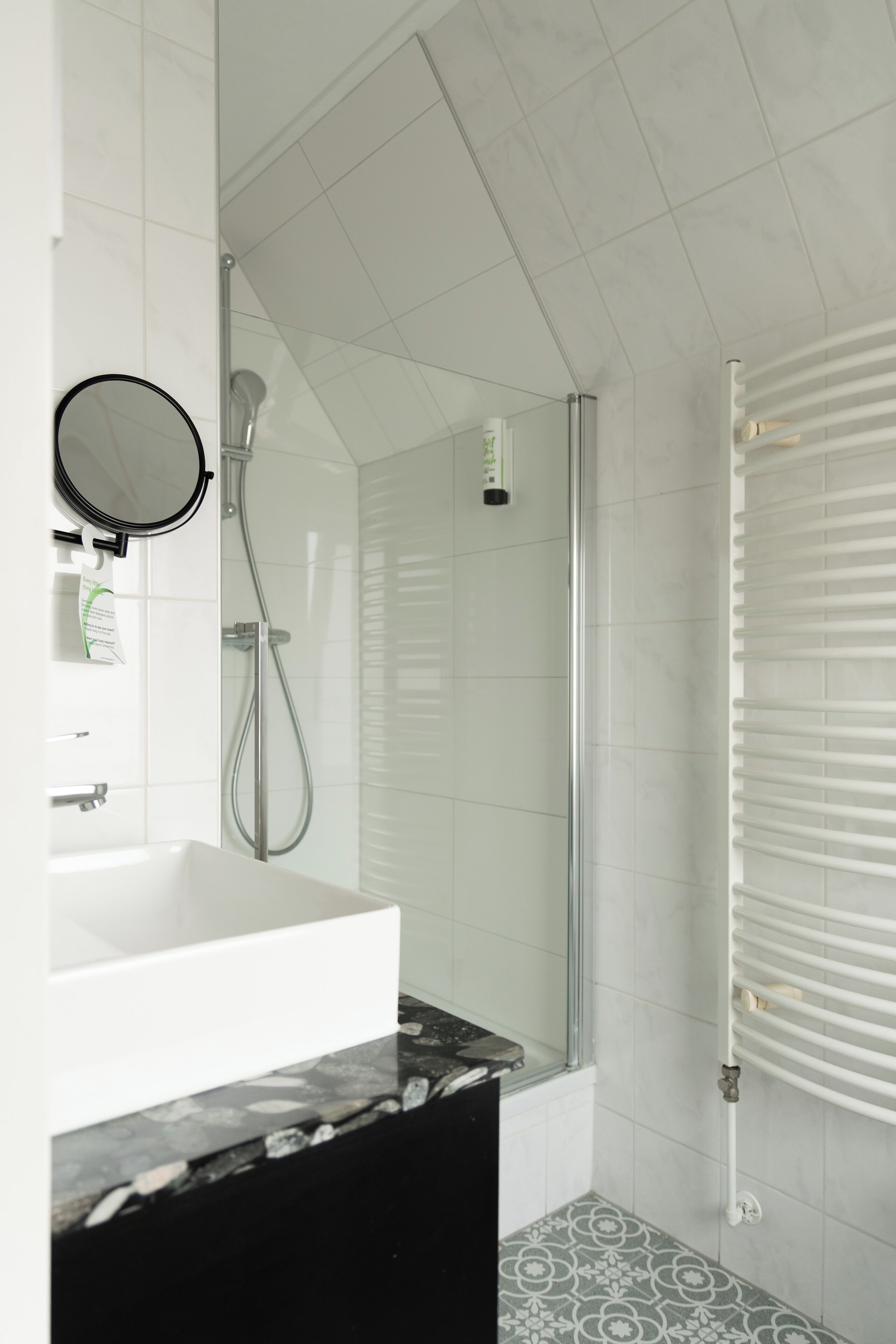 Une salle de bain moderne avec un lavabo blanc, une douche en verre et un carrelage décoratif.