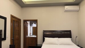 A bedroom with a bed, a nightstand, a wooden door, a mirror, and an air conditioning unit. - Ensenada’s Luxury Ocean Front Property. 1or 2 condominiums available. (Ensenda)