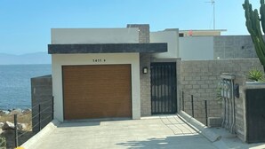 A modern building with a garage, a view of the sea, and a cactus in the foreground. - Ensenada’s Luxury Ocean Front Property. 1or 2 condominiums available. (Ensenda)