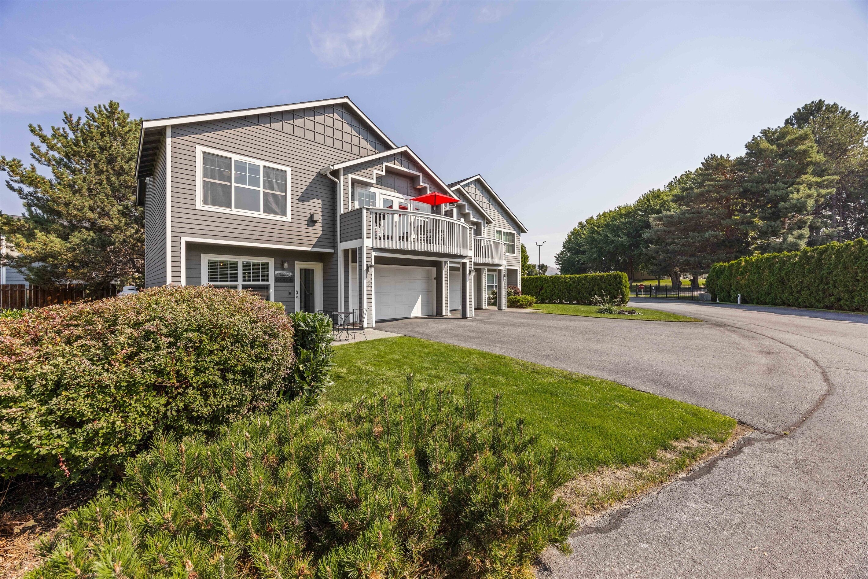 A two-story house with a balcony, a garage, and a well-maintained lawn.