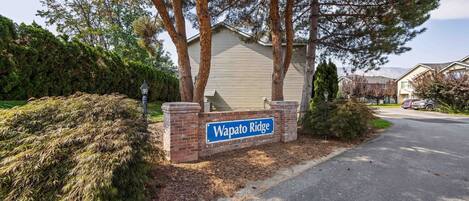 A sign for Wapato Ridge with a paved driveway and surrounding trees.