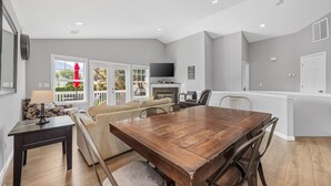 Cozinha moderna com mesa de jantar de madeira, eletrodomésticos embutidos e uma grande janela com vista para um deck.