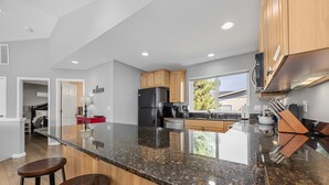 Uma cozinha moderna com bancadas de granito, armários de madeira e eletrodomésticos de aço inoxidável.